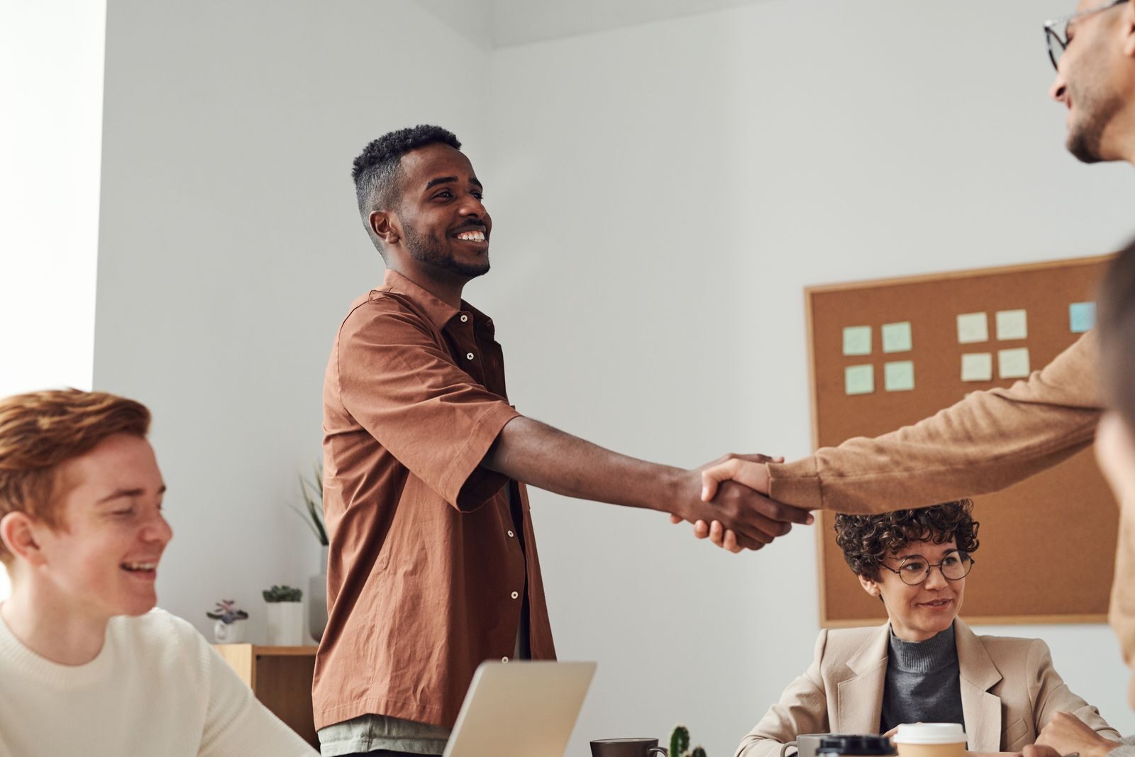 Photo by fauxels Business team members shaking hands during a meeting, demonstrating cooperation and teamwork.